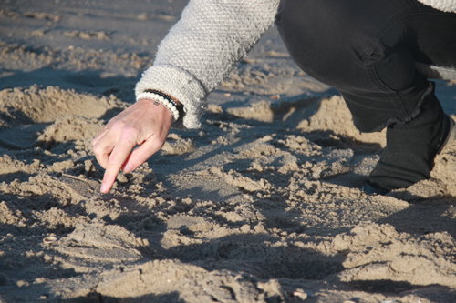 Vrouw maakt tekening in het zand op het strand